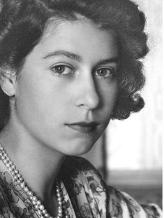 an old black and white photo of a woman with pearls on her necklace, looking at the camera