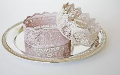 two pink lace bracelets sitting on top of a silver plate next to each other