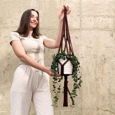 a woman holding a plant hanging from a wall