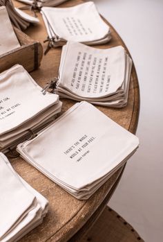 several folded napkins on top of a wooden table with words written on the paper