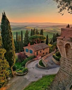 an aerial view of a small village with trees and hills in the background at sunset