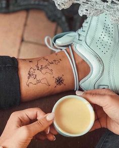 a person with a tattoo on their arm holding a coffee cup