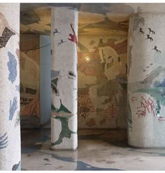 several pillars with designs on them and birds painted on the wall in front of them