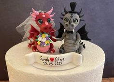 a wedding cake topper with two dragon figurines sitting on it's side