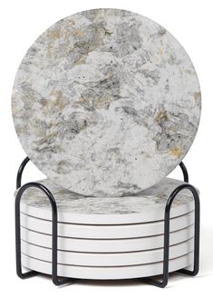 a stack of white marble plates sitting on top of black metal stands with two round bases