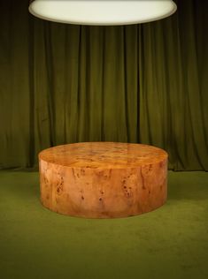 a round wooden table sitting on top of a green carpeted floor next to a lamp