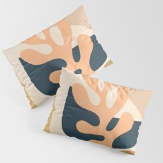 two decorative pillows on white background with blue, pink and beige shapes in the shape of leaves