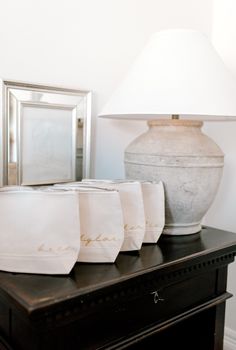 three white napkins sitting on top of a table next to a vase and mirror