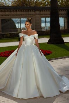 a woman in a white wedding dress is walking down the street with her hand on her hip