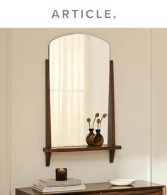 a mirror sitting on top of a wooden dresser next to a vase filled with flowers