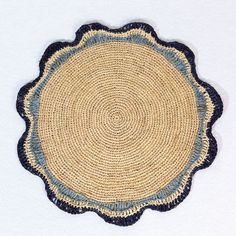 a round woven placemat with blue and beige trimmings on a white surface