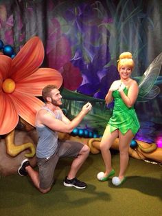 a man and woman dressed as tinkerbells in front of a flower backdrop