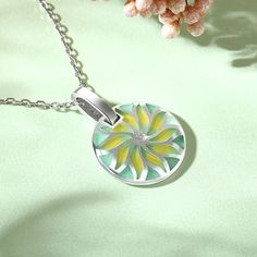 The motif of the compass flower radiating in gold loses itself in infinity, just like the sea does. A pretty necklace made from sterling silver and green&yellow enamel tones. The necklace is decorated with a delicate floral motif that radiates from its center. Elegant design.Carat Weight: 0.135 ctStone Size: 1,1.75 mmNumber of Stones: 10 Stone Shape: RoundStone Color: Diamond WhiteWeight: 3.1 gWidth: 15.9 mmHeight: 22.9 mmThickness: 4.9 mmMaterial: 925 SilverStone Type: Jeulia® StonePlating Colo Green Necklace With Flower Charm And Round Pendant, Green Round Pendant Clavicle Chain, Green Clavicle Chain With Round Pendant, Green Necklace With Large Medallion Pendant, Green Pendant Necklace With Flower Charm, Green Flower Charm Jewelry With Round Pendant, Green Flower Charm Round Pendant Jewelry, Nickel-free Green Flower Pendant Jewelry, Green Round Pendant Jewelry With Flower Charm