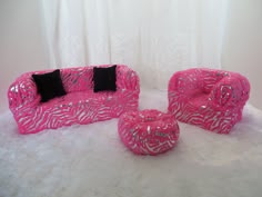 a pink couch and chair sitting on top of a white fur covered floor next to a black pillow