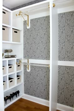 a walk in closet with white shelves and drawers