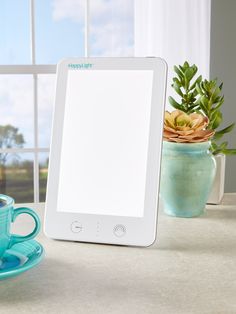 a tablet computer sitting on top of a table next to a cup and saucer