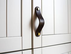 a close up of a kitchen cabinet door handle on a white cupboard with yellow knobs