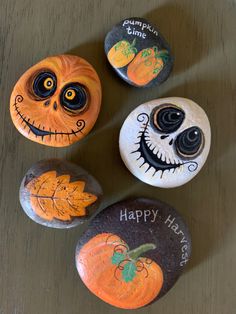 four painted rocks with pumpkin faces on them