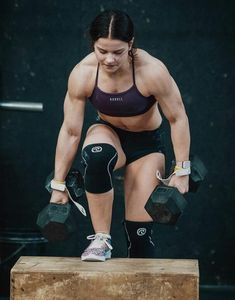 a woman is doing exercises with dumbbells on a wooden box in the gym