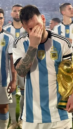 a soccer player covers his face with his hands as he stands in front of other players