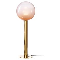 a pink glass ball sitting on top of a gold metal stand lamp with a white base