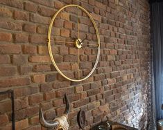 a clock mounted to the side of a brick wall next to an old fashioned sink