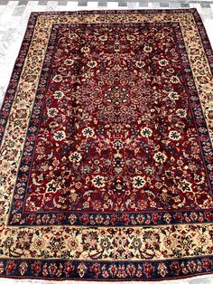 an antique persian rug is on display in a room with tile flooring and white walls