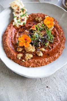 a white bowl filled with food and garnished with orange flowers on the side