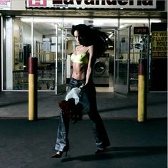 a woman walking down the street in front of a laundment holding a bouquet of flowers