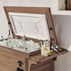 an open wooden box filled with lots of bottles and glasses on top of a table