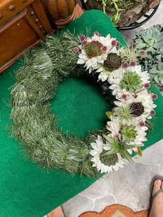 a person standing next to a green rug with flowers on it and plants in the background