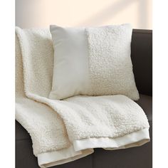 a white blanket sitting on top of a couch next to a pillow and two pillows