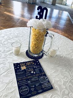 a table topped with a glass mug filled with rice next to a chalkboard sign