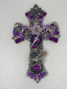 a purple and silver cross with flowers on it