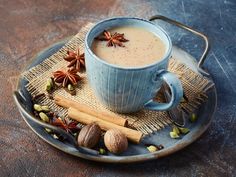 a cup of coffee with cinnamon, star anise and cloves on a plate