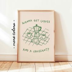 a framed poster on the floor with coffee and croissants written in green