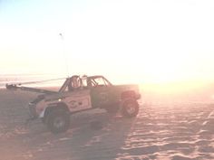 an off road vehicle driving on the beach at sunset or sunrise with fog in the air