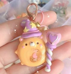 a hand holding a small yellow bear with a purple hat