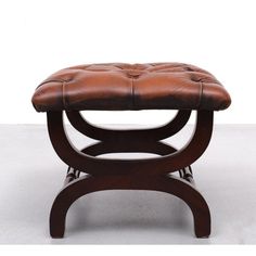 a brown leather foot stool sitting on top of a white floor