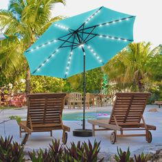 two lawn chairs and an umbrella with lights on them in front of a swimming pool