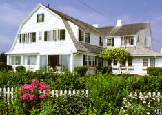 a white house surrounded by greenery and flowers