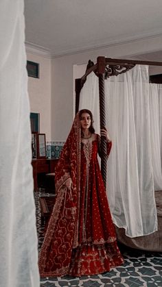 a woman standing in front of a canopy bed