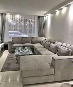 a living room filled with lots of couches and a large tv mounted to the wall