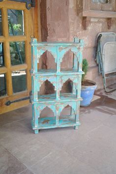 an old blue bookcase sitting on the ground in front of a building with glass doors