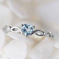 a heart shaped blue topazte ring sitting on white flowers