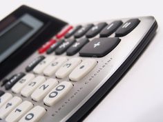 a calculator sitting on top of a white table next to a cell phone