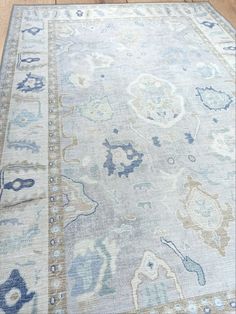 an area rug with blue and beige colors on the floor in front of a wooden floor