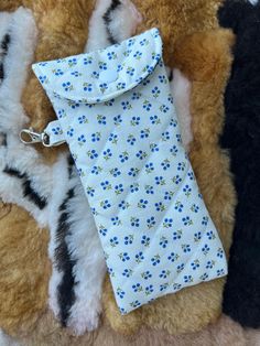 three different colored teddy bears laying next to each other on a rug with a blue and white flowered tie hanging from it's end