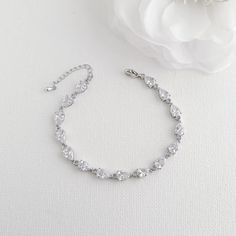 a white flower sitting next to a silver bracelet