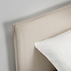 a close up view of a bed with white sheets and pillows on the headboard